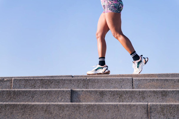 cropped photo of the legs of an unrecognizable african american woman running outdoors, concept of sports and active lifestyle, copy space for text - Fotografie, Obrázek