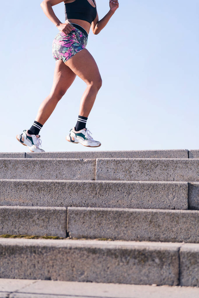 vertical cropped photo of the legs of an unrecognizable african american woman running outdoors, concept of sports and active lifestyle, copy space for text - Photo, Image