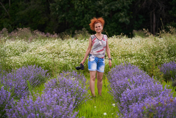 Woman nature photographer with her camera in a lavender field shooting pictures - Фото, зображення