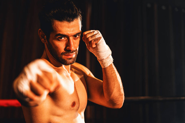 Boxkämpfer ohne Hemd posiert, kaukasischer Boxer schlägt seine nackte Faust und wickelt sich vor der Kamera, aggressive Haltung und bereit, im Boxring zu kämpfen. Impulse - Foto, Bild