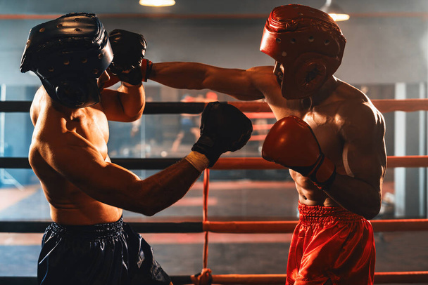Dos boxeadores deportivos y musculosos con casco de seguridad o protector de cabeza de boxeo se enfrentan en un feroz combate de boxeo. Luchador de boxeo competidor luchando en el ring de boxeo. Impulso - Foto, imagen