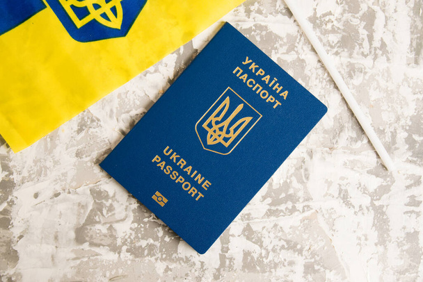 Flatlay, ukrajinský pas a vlajka na světlém betonovém pozadí s kopírovacím prostorem. - Fotografie, Obrázek