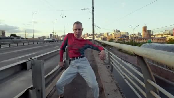 Miejscowy facet tańczący freestyle na moście. Styl życia tancerki w miejskim krajobrazie to rytmiczne ruchy w rytm muzyki. Wysokiej jakości materiał 4k - Materiał filmowy, wideo