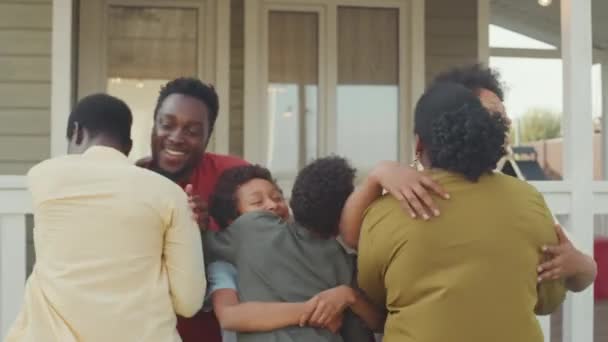 Средний снимок двух счастливых афроамериканских пар с 11-12-летними детьми, встречающимися на крыльце, приветствующими и обнимающими друг друга - Кадры, видео