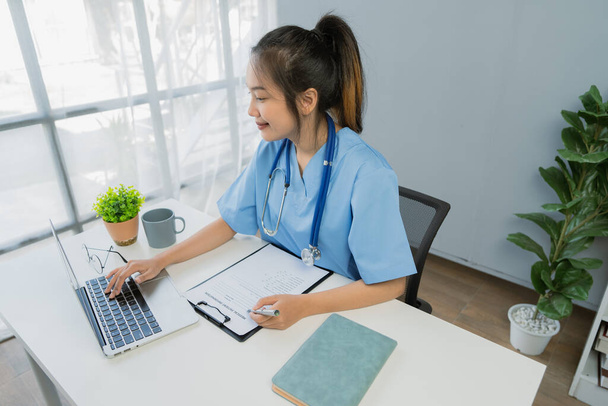 Profissional jovem mulher asiática médico usando laptop trabalhando na mesa na clínica. - Foto, Imagem