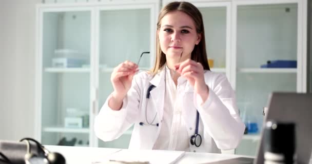 Επαγγελματίας ειδικός με στηθοσκόπιο βάζει γυαλιά κατά τη διάρκεια του διορισμού σε ιατρικές εγκαταστάσεις. Γυναίκα γιατρός λαμβάνει ασθενείς στο γραφείο αργή κίνηση - Πλάνα, βίντεο