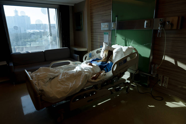 窓から差し込む陽射しが病院のベッドに横たわっている患者 - 写真・画像