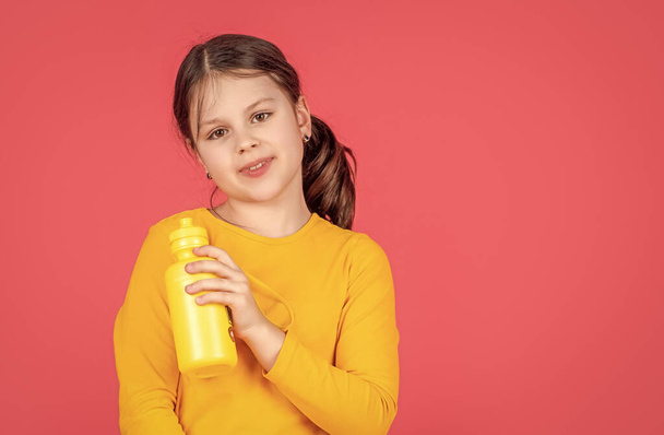 smiling kid hold water bottle on pink background. - Фото, зображення