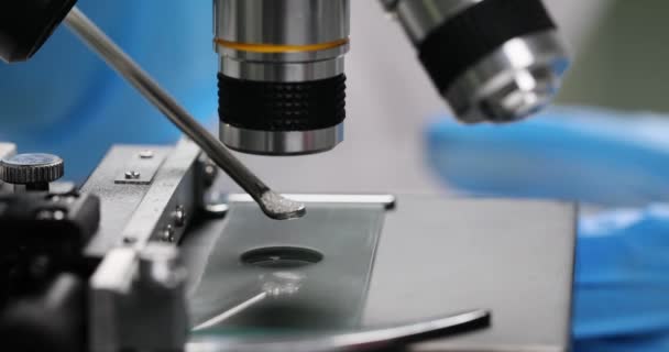 Specialist onderzoekt kristallijn granulaat onder microscoop in het laboratorium. Wetenschapper in rubber handschoenen doet wetenschappelijk onderzoek slow motion - Video