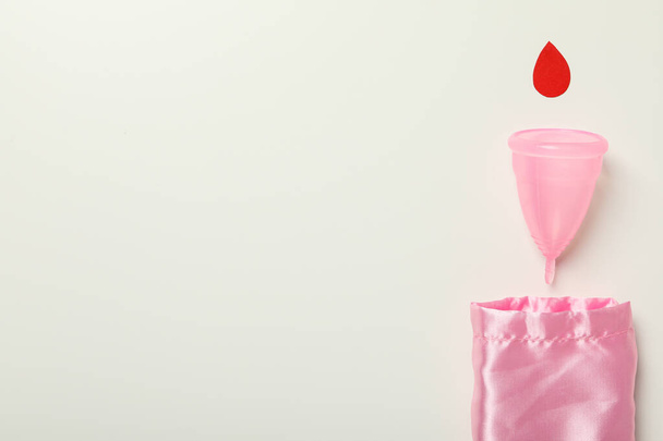 Coupe menstruelle avec une goutte rouge sur fond blanc - Photo, image