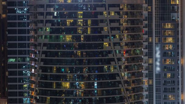 Residential buildings windows illuminated at night timelapse. Glass architecture, corporate building at evening with glowing lights - Фото, изображение