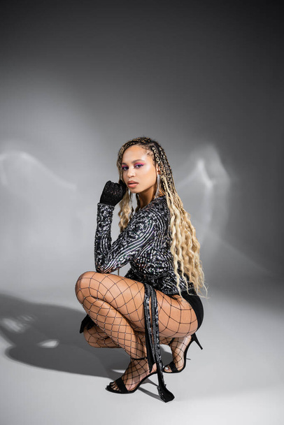 diversity, african american woman in gloves and fishnet tights, posing on grey background, style - Foto, immagini