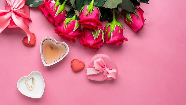 Top pohled na Valentýna dárek s vínem a růžovou růží kytice na růžové pozadí designu koncepce - Fotografie, Obrázek
