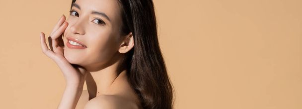 Young long haired asian woman smiling and looking at camera isolated on beige, banner - Фото, изображение