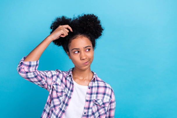 Portrait of clever smart teenager afro hair plaid shirt finger on head thoughtfully look empty space isolated on blue color background. - Fotografie, Obrázek