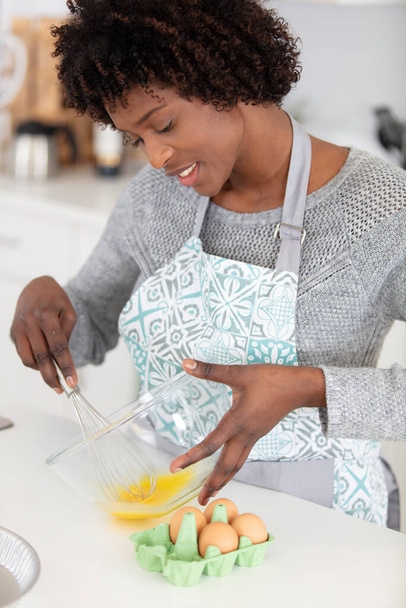 cheerful woman whisks eggs at home - Photo, image