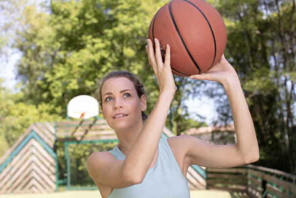 young woman ready to throw basketball into loop - Фото, изображение