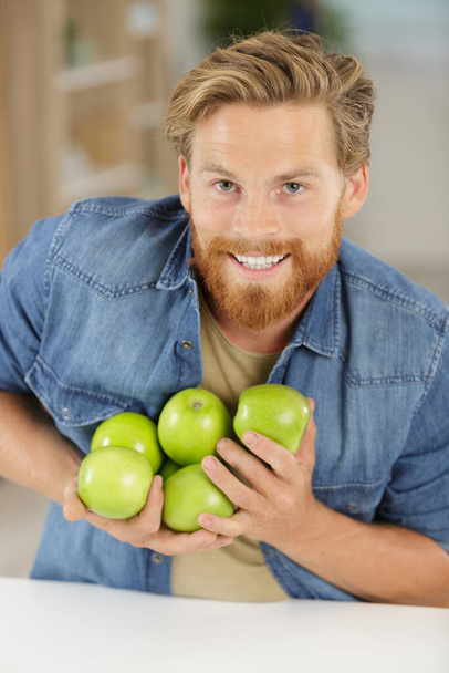 happy young man holding green apples - Фото, изображение
