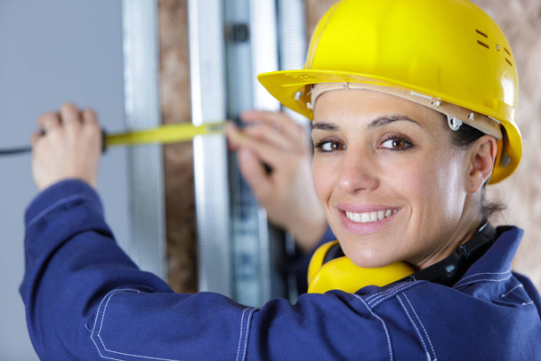 woman worker measuring dimensions on plasterboard panel - 写真・画像