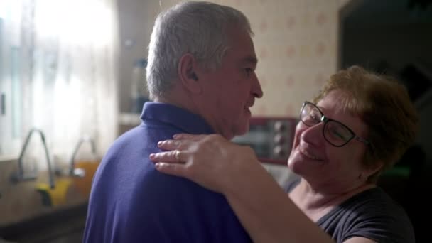 Křehký moment seniorského páru Tancování doma, manžel a žena v milujícím objetí v kuchyni - Záběry, video