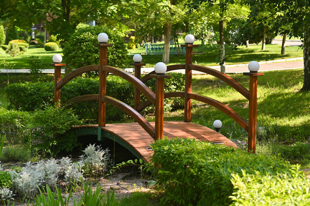 красивый деревянный мост с фонарями в парке - Фото, изображение