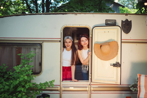 Gelukkige hippie vrienden hebben een leuke tijd samen in een camper trailer. Vakantie, vakantie, reisconcept. Hoge kwaliteit foto - Foto, afbeelding