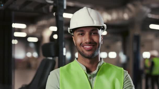 Multi-Ethnic Man Worker in Protective Yellow Vest Looking at Camera. Engineer Standing and Posing with Crossed Arms in Background in the Plant of Factory - Imágenes, Vídeo