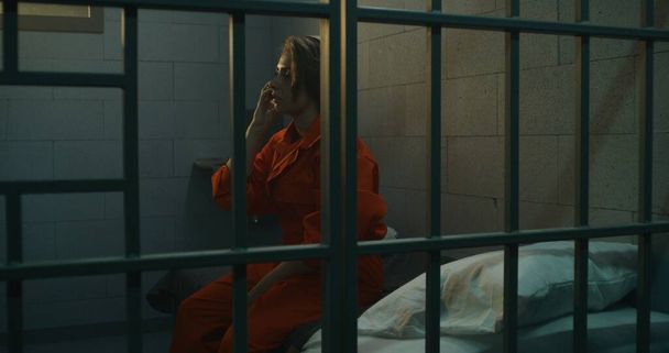 Female prisoner talking phone in prison. Women serve imprisonment term in jail. Detention center or correctional facility. - Photo, Image