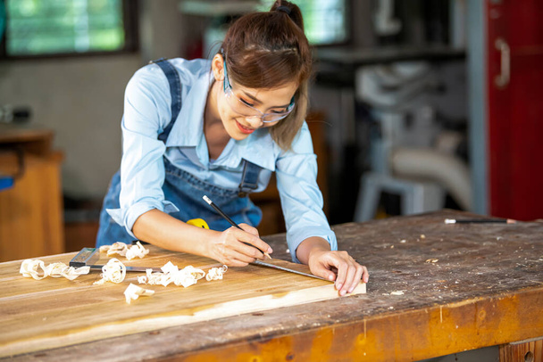 A carpenter uses equipment on a wooden table in a carpentry shop. woman working in a carpentry shop - Photo, Image
