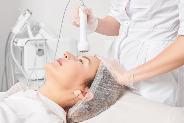 Beautician makes RF lifting for rejuvenation woman face, anti aging cosmetic procedure in beauty spa salon. Cosmetologist makes radio frequency treatment for collagen increasing on female face skin - Photo, Image