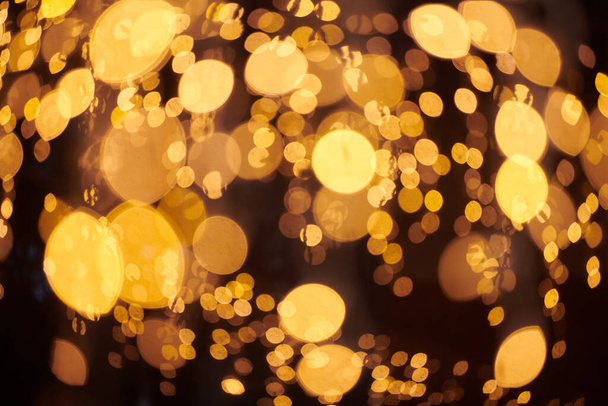 Luci gialle bokeh da ghirlande natalizie, sfondo festivo sfocato, luci esterne astratte con boke. Luminose luci giallo bokeh con bella lucida su sfondo notte scura - Foto, immagini