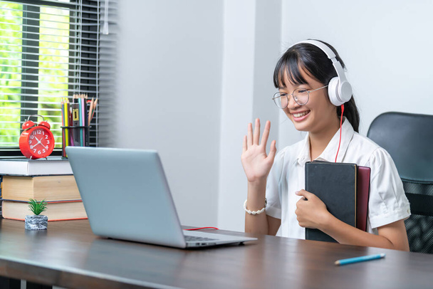 Boldog mosolygó női diák fülhallgatót visel beszél az online megbeszélés segítségével laptop otthoni irodában. női főiskolai hallgató tanul távoktatás üzleti - Fotó, kép