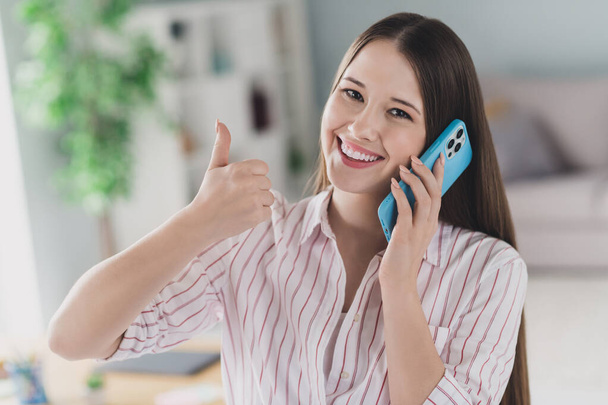 Photo portrait of attractive young woman talk phone chat thumb up dressed stylish smart casual clothes interior cozy room home office. - 写真・画像