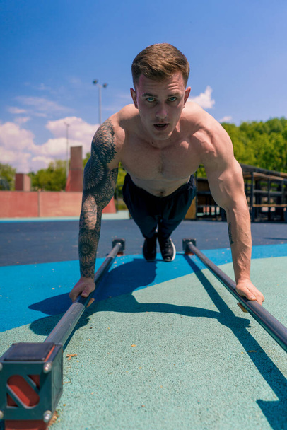 fiatal felpumpált sportoló csinál push-up a földről alatt utcai edzés állóképesség gyakorlása hinták karok vállak - Fotó, kép