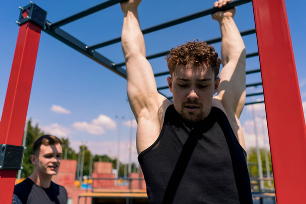 Persönlicher Fitnesstrainer oder Bodybuilder schult junge Sportler bei der Sportplatzmotivation - Foto, Bild