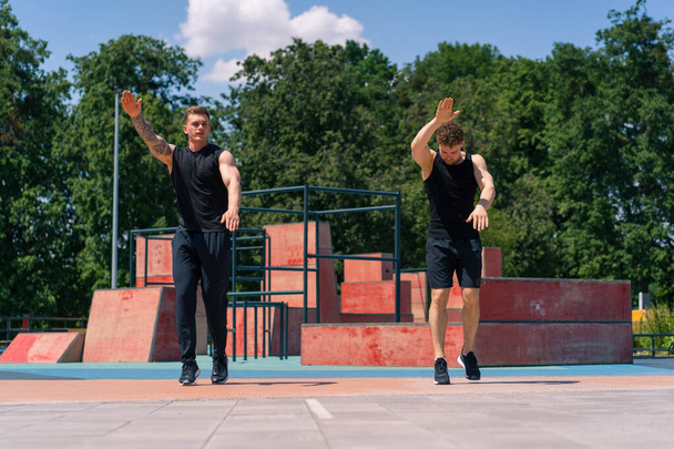 Henkilökohtainen kunto kouluttaja koulutus urheilija urheilukentällä Kaksi aktiivista hikinen kaveri hyppääminen ulkona tekee harjoituksia - Valokuva, kuva
