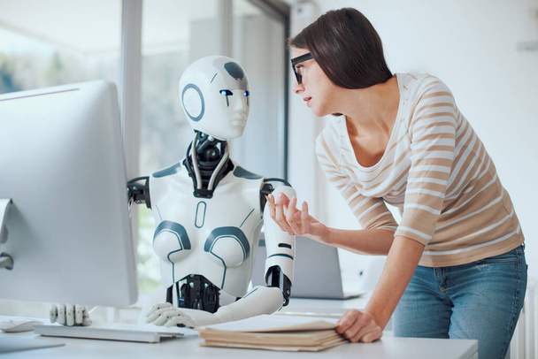 Woman and AI robot working together in the office, automation and technology concept - Photo, image