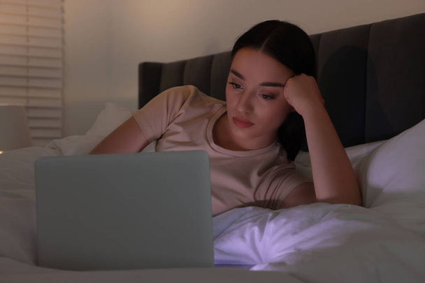 Young woman using laptop in bed at night. Internet addiction - Zdjęcie, obraz