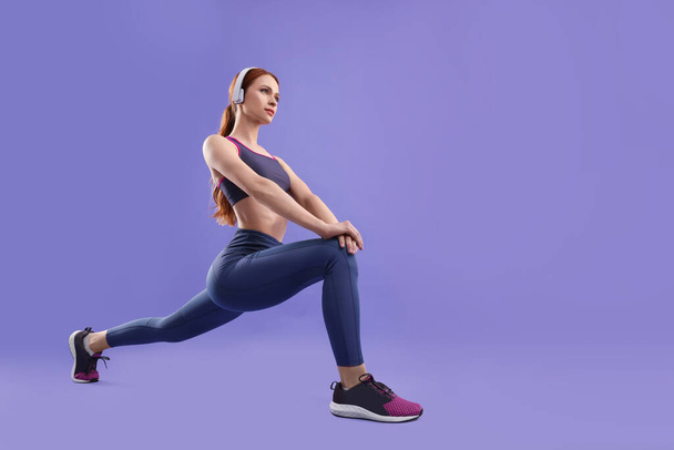 Woman in sportswear doing exercises on violet background, space for text - Foto, Imagem