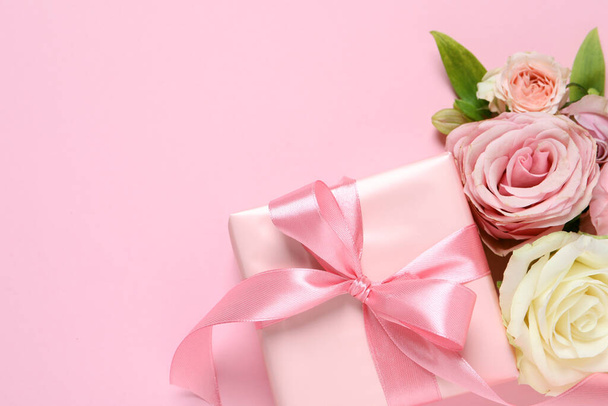 Gift box and beautiful flowers on pink background, flat lay. Space for text - Foto, immagini