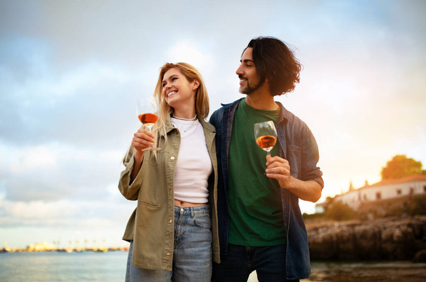 ロマンチックな若いカップルがアウトドア,ハッピーミレニアルマン,外で楽しむ女性,サンセットタイムでビーチでリラックス,記念日を祝う,無料スペース - 写真・画像