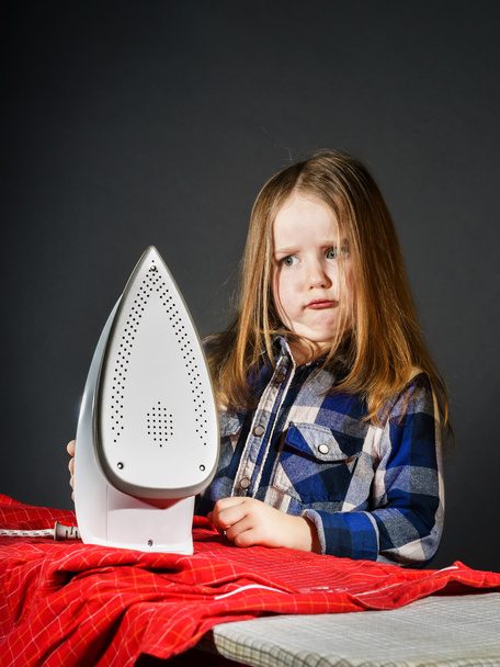 niedliches kleines Mädchen, das deiner Mutter hilft, indem es Kleidung bügelt, - Foto, Bild