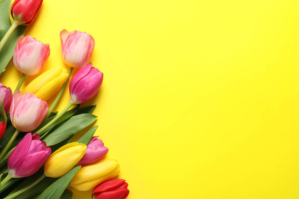 Beautiful colorful tulip flowers on yellow background, flat lay. Space for text - Foto, immagini
