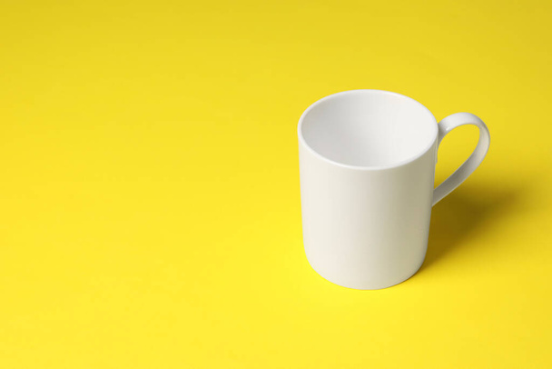 One white ceramic mug on yellow background, space for text - Photo, image
