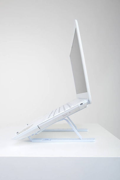 Μόνιμη θήκη laptop που έχει συσταθεί με σημειωματάριο στο γραφείο - Φωτογραφία, εικόνα