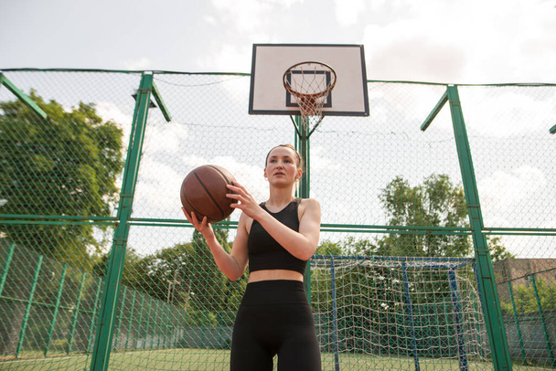 Αθλητική γυναίκα μπασκετμπολίστας ρίχνει μια μπάλα στο δίχτυ. - Φωτογραφία, εικόνα