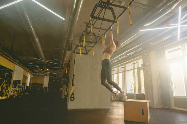 Une jeune femme forte se tire vers le haut et fait un entraînement dans la salle de gym. Photo de haute qualité - Photo, image