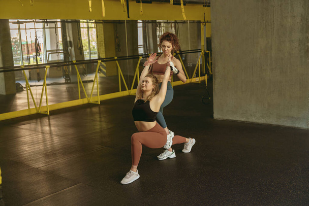 Fit woman doing stretching exercises with the help of personal trainer at gym. High quality photo - Fotó, kép