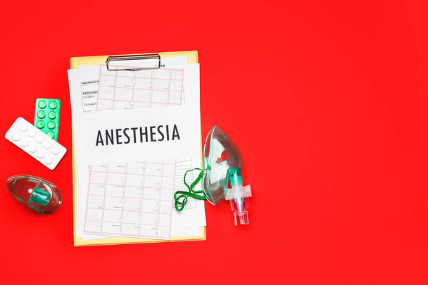 Üzerinde anestezi yazan pano, kırmızı arka planda haplar ve oksijen maskeleri. - Fotoğraf, Görsel