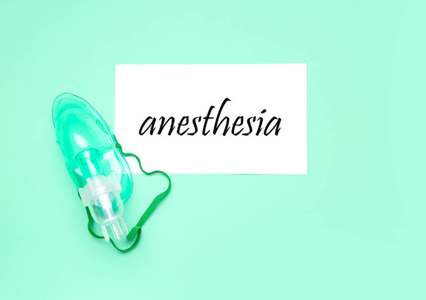 Papel con palabra ANESTESIA y máscara de oxígeno sobre fondo verde - Foto, imagen
